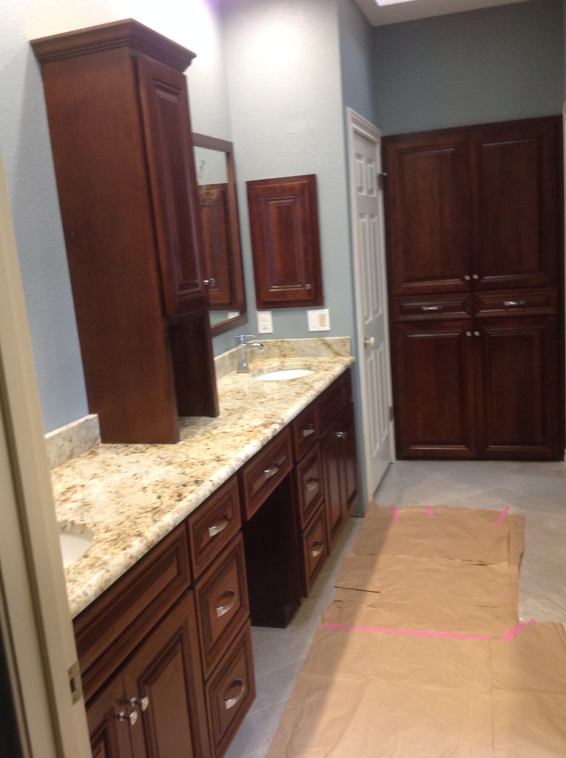 Elegant bathroom vanity cabinets installed beside a bright mirror in a remodeled home